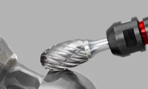 Metalowy frez z ostrymi nacięciami zbliża się do metalowego elementu, gotowy do precyzyjnej obróbki.