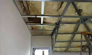 Konstrukcja podwieszanego sufitu z metalowymi profilami i izolacją piankową, gotowa do dalszych prac wykończeniowych.
