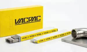 Żółte pudełko z logo VACPAC, obok opakowania z elektrodami spawalniczymi i metalowym kolankiem.