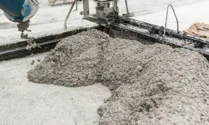 Beton wylewany z betoniarki na podsypkę z piasku pod kostkę.