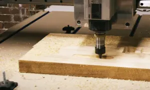 CNC frezarka pracuje nad drewnem, tworząc rowki. Różne rodzaje frezów pozwalają na precyzyjne kształtowanie materiału.