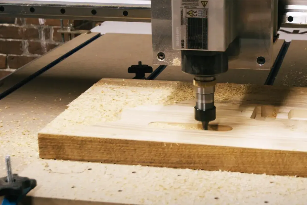 CNC frezarka pracuje nad drewnem, tworząc rowki. Różne rodzaje frezów pozwalają na precyzyjne kształtowanie materiału.