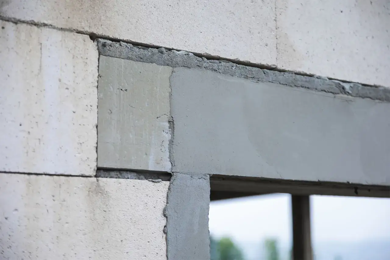 Fragment budowy z widoczną betonową framugą okienną, wykonaną z bloczków gazobetonowych i zaprawy.
