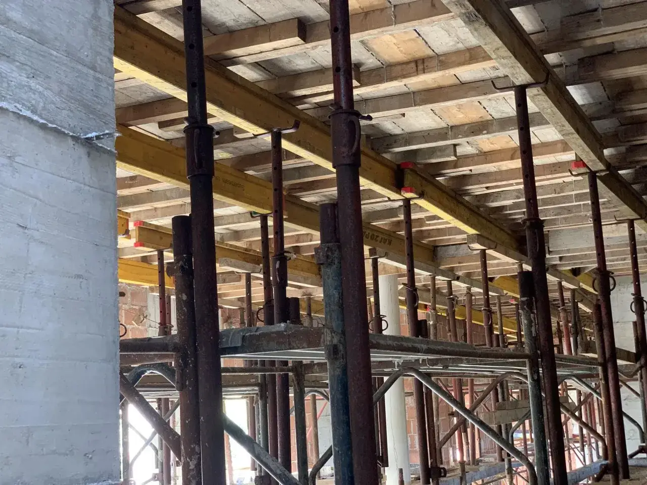Konstrukcja pod strop monolityczny: drewniane belki, metalowe podpory i szalunki tworzą rusztowanie.