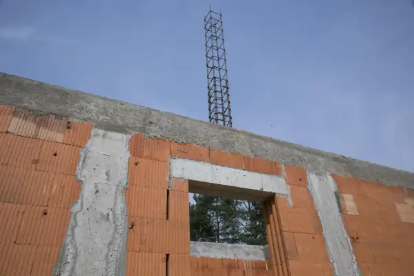 Budowa domu w toku: wieniec stropowy z betonu i zbrojenia, ściany z pustaków ceramicznych, widok na okno i niebo.