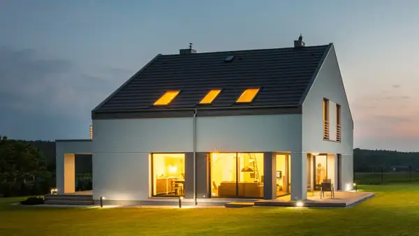 Nowoczesny dom z jasnym, gładkim tynkiem zewnętrznym, który podkreśla jego architekturę. Różne rodzaje tynków zewnętrznych mogą nadać budynkowi unikalny charakter.