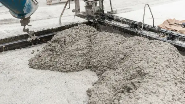 Beton wylewany z betoniarki na podsypkę z piasku pod kostkę.